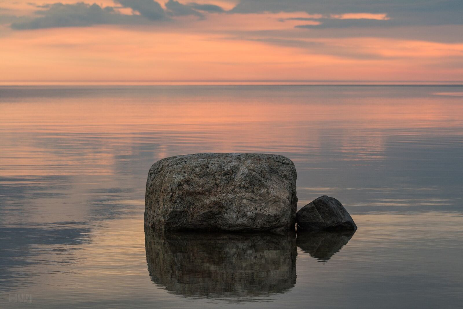 Rocks rise from calm water beneath a pastel sunset sky, representing peace after betrayal.