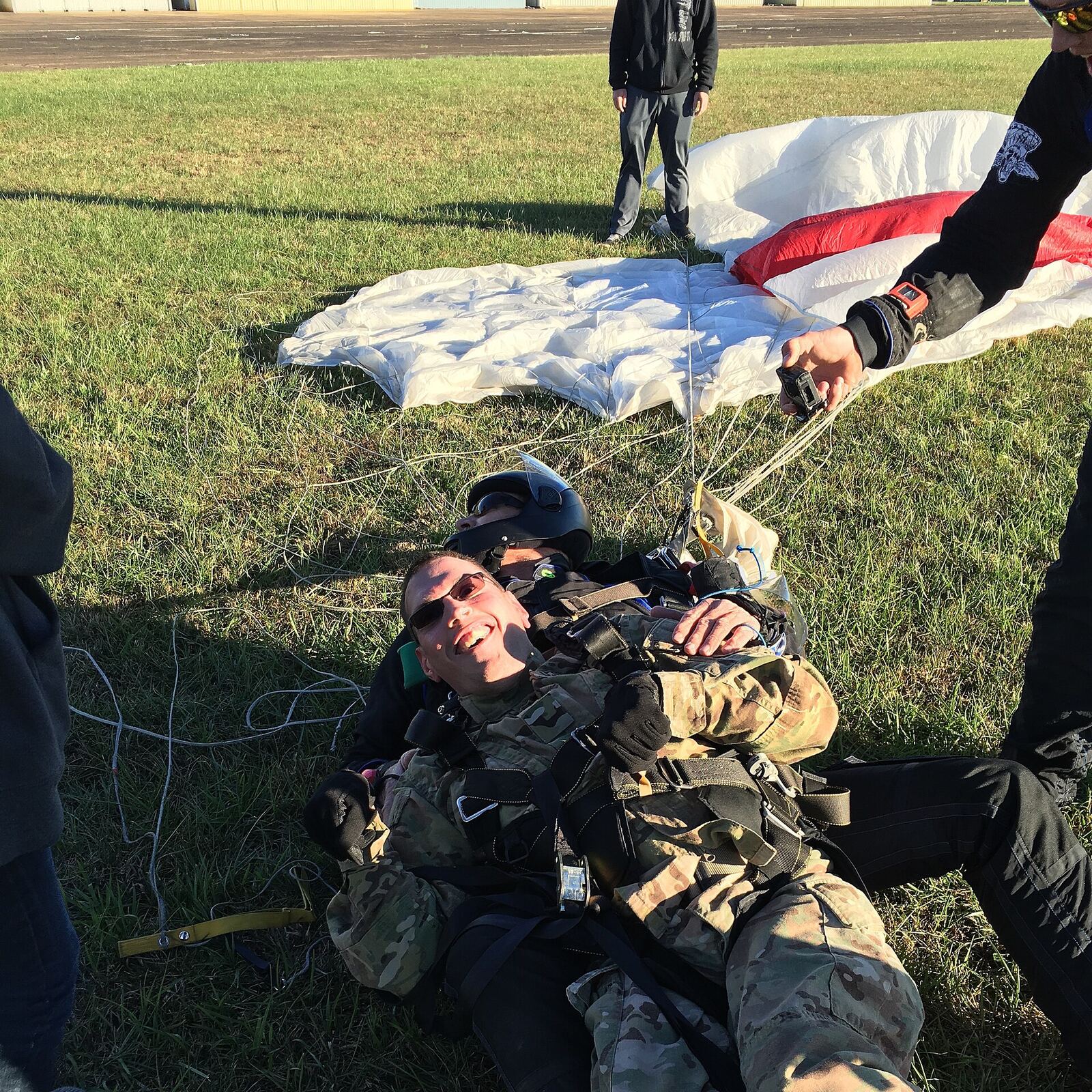 Paratrooper | Love Hurtz A paratrooper smiles after a successful parachute landing, representing resilience and trauma recovery.