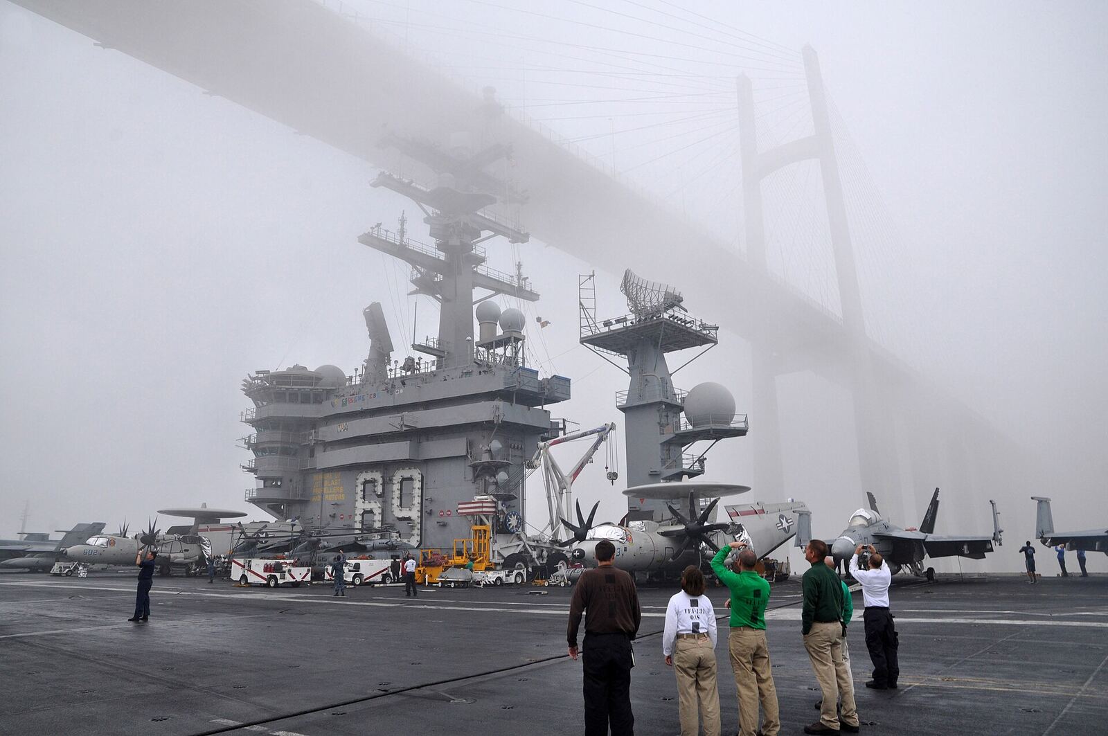 USS Dwight D. Eisenhower | Love Hurtz An aircraft carrier passes under a bridge in thick fog, representing the obscured path through trauma.